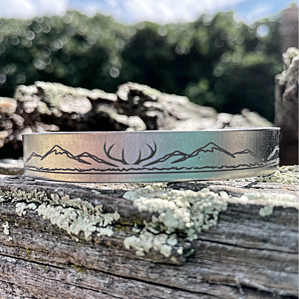Cuff bracelet with mountain design on a stainless steel surface